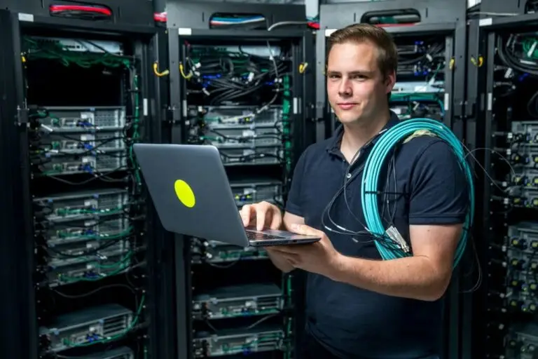 IT Professionals - an open letter - IT worker on laptop in front of data stack