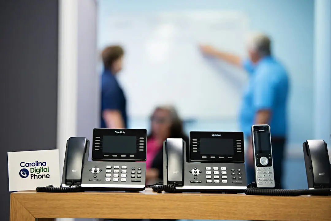 cyberattacks - best practices - blurred people in background behind 3 different phones and business card