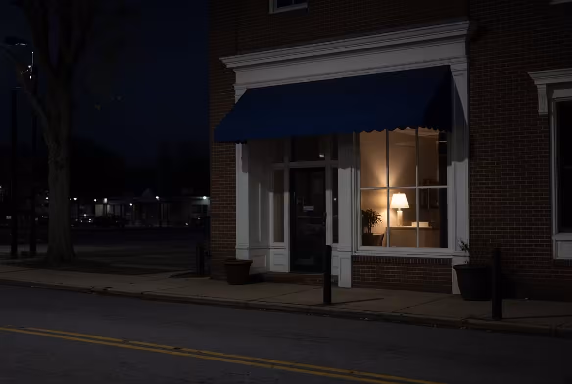 Brick North Carolina storefront at night with a single lamp glowing in the reception window